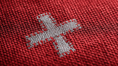 This close-up image features a striking red fabric adorned with a silver cross stitch pattern, highlighting the intricate details and craftsmanship of textile art.の素材