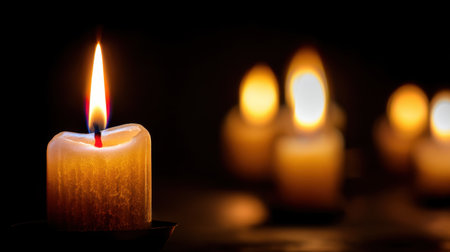 A close-up of a single candle burning brightly, casting a warm glow in a dark setting. The flickering flame creates a tranquil ambiance, perfect for relaxation and meditation.の素材