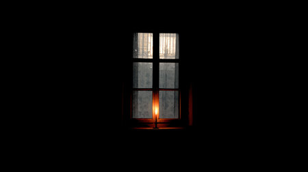 A serene scene featuring a single candle flickering softly beside a dark window, casting a warm glow on dusty glass, evoking feelings of calm and solitude.の素材