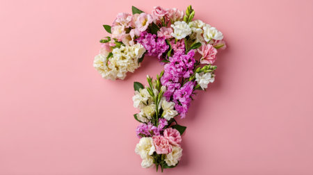 This beautiful arrangement of flowers in the shape of a question mark stands out against a pink background, evoking curiosity and creativity.の素材