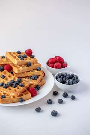 Traditional Belgian waffles with blueberries and raspberries for breakfastの写真素材