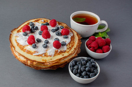 french pancakes with berries and a cup of mint teaの写真素材