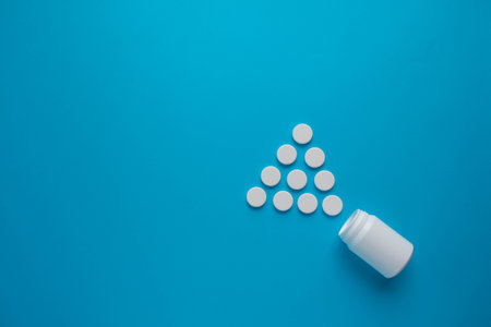 Plastic medical container and white pills on blue background top view. Medical and health concept. 3d rendering.の写真素材