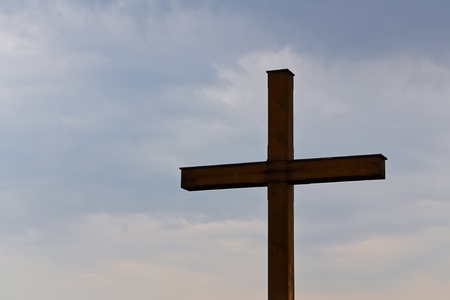A wooden cross in front of blue and cloudy sky at a cemetary in lower austriaの写真素材