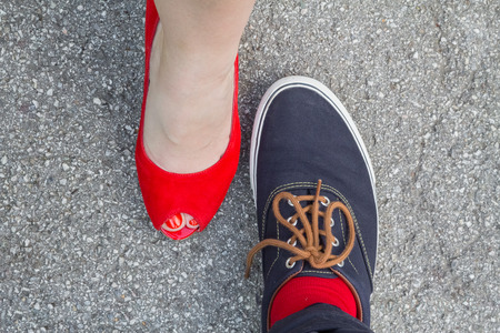 Shoes of a woman and a man standing opposite each other - red is the unifying colorの写真素材
