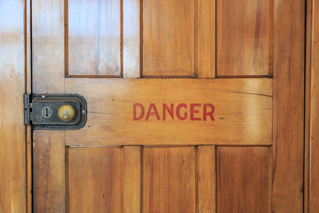 An old wooden closed door with red letters saying danger printed on itの写真素材
