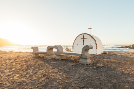A little chapel with a cross and benches at the coast of Fuerteventura (Spain) at duskの写真素材