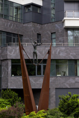 Metal ropewalker girl statue with an office building on the backgroundの写真素材