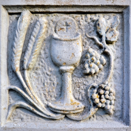 Religion scene with chalice, grain and grapes in stoneの写真素材