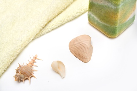 Soft yellow towel, ocean salt and seashells on white backgroundの写真素材