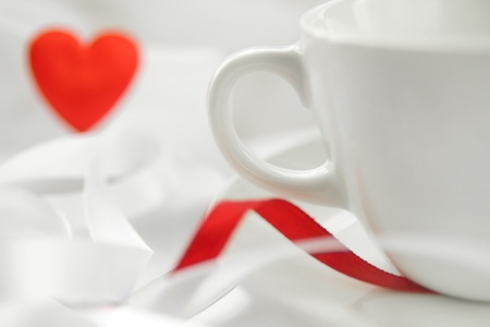 Romantic background with white cup and defocused red heart. Soft focusの写真素材