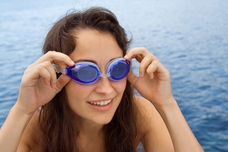 Young girl with swimming glasses near the seaの写真素材