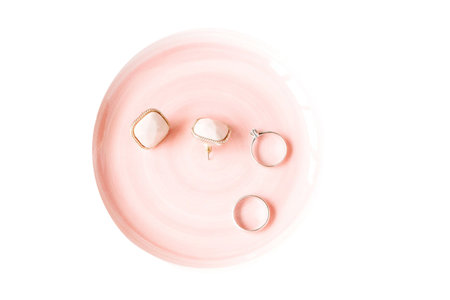 wedding rings on a pink plate isolated on a white backgroundの写真素材