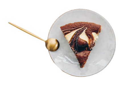 Piece of chocolate cake on a plate with spoon isolated on white backgroundの写真素材