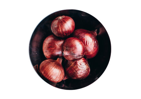 Red onion in a black bowl isolated on white background. top view.の写真素材
