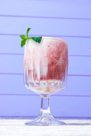 Shake in a glass with syrup and straws on a wooden tableの写真素材