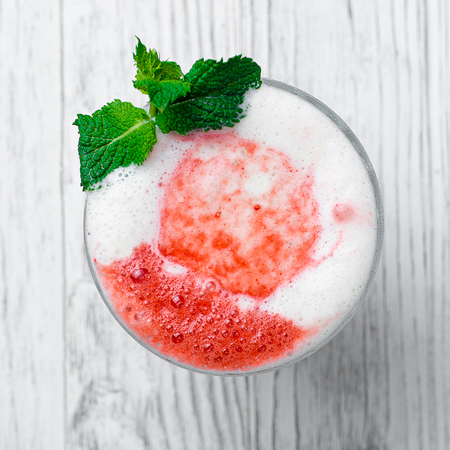 Shake in a glass with syrup and straws on a wooden tableの写真素材
