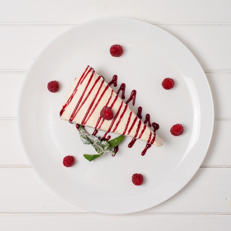 Cheesecake with raspberry mint and jam on a wooden table.