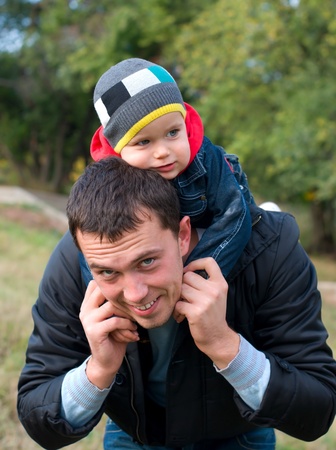 Happy father and son in a park in autumnの写真素材
