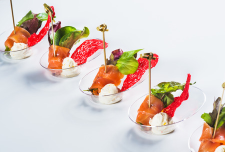 Salmon snack with soft cheese, fresh salad and basil on light backgroundの写真素材