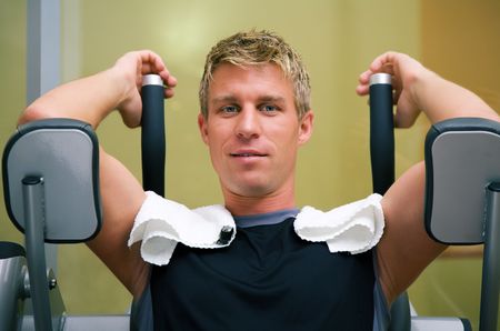 Man at the machine in a gym having a break