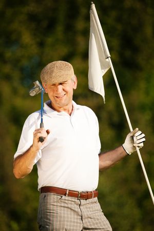 Senior man playing golf holding the flag in his handの写真素材