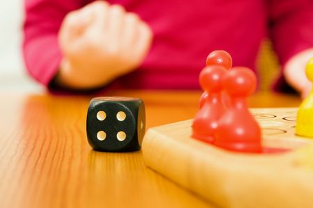 Family (only hand of child to be seen) playing a board game, child having exactly the right number...