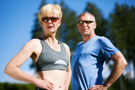 Mature or senior couple in jogging gear doing sport and physical exercise outdoorsの写真素材