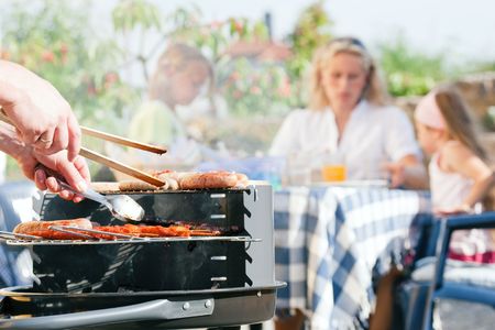 Family having a barbecue in the garden - focus on cooking in the foregroundの写真素材