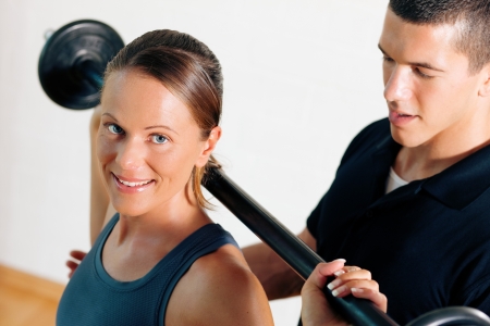 Woman with her personal fitness trainer in the gym exercising power ...