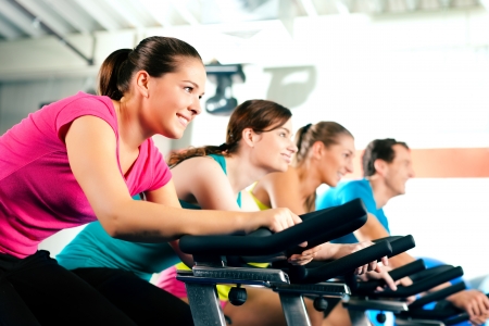 Group of four people spinning in the gym, exercising their legs doing cardio training