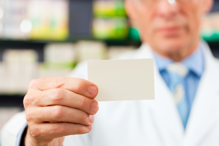 Pharmacist with business card in pharmacy; focus on cardの写真素材