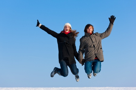 Couple - man and woman - jumping high on a winter dayの写真素材