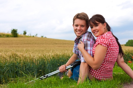 Young fitness couple doing sports outdoors; making a break from hiking in summer の写真素材