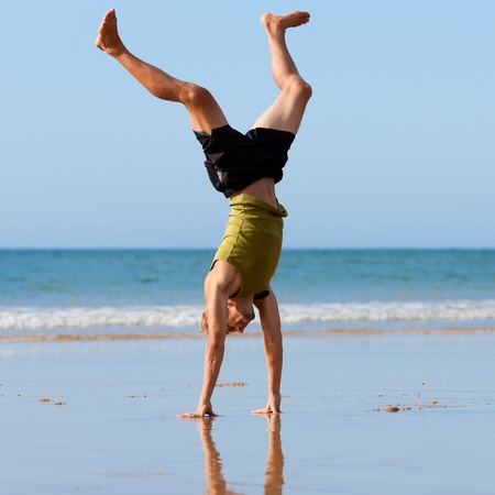 Young sportive man doing gymnastics on the beachの写真素材