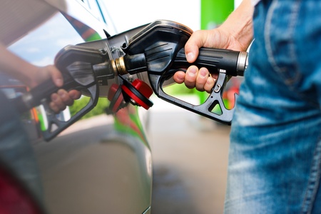 Refuel the car on a gas station; man holding the tap