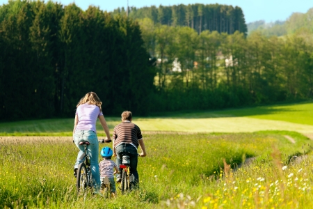 Family with boy child having a weekend excursion on their bikes on a summer day in beautiful landscapeの写真素材