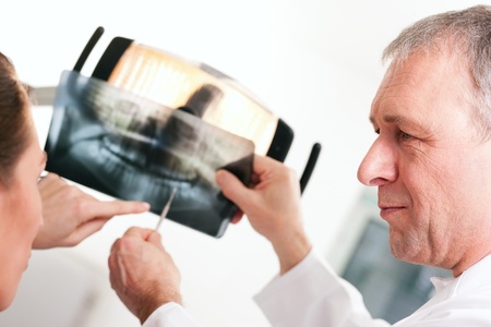 Dentist explaining the details of a x-ray picture to his patient