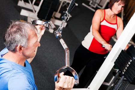 Senior people in a gym exercising on a pulldown machine  の写真素材
