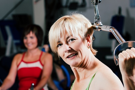 Senior woman in the gym lifting weights on a lat pull machine, exercisingの写真素材