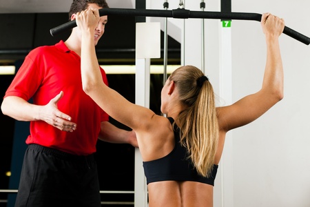 Woman in gym with personal fitness trainer exercising power gymnastics 