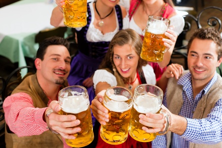 Inn or pub in Bavaria - group of five young men and women in traditional Tracht drinking beer and having a party with beerの写真素材