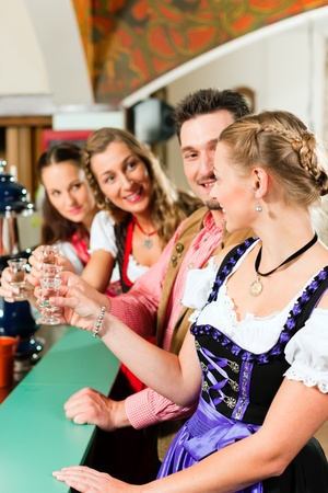 People in Bavarian Tracht drinking hard liquor in a pub and have funの写真素材