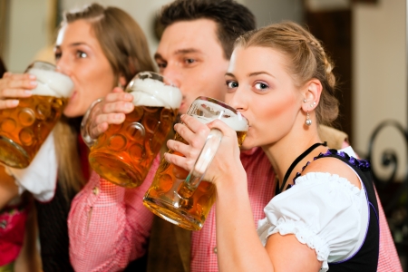 Inn or pub in Bavaria - group of three young people in traditional Tracht drinking beer の写真素材