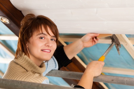 Woman doing dry walling, working under a roof slopeの写真素材