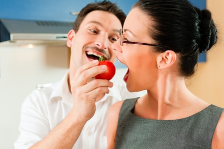 Young couple - man and woman - cooking in their kitchen at home, they teasing each other の写真素材