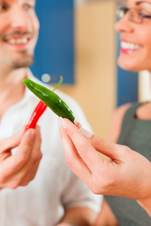 Young couple - man and woman - cooking in their kitchen at home, they having funの写真素材