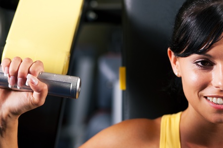 Very fit and beautiful young woman in a gym working out and lifting weights on an exercising machine