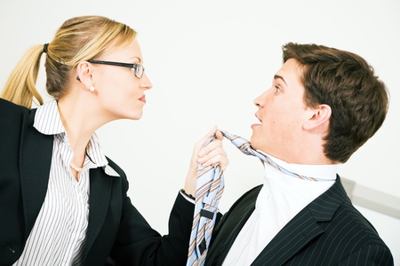 Businesswoman grabbing her colleague at his tieの写真素材