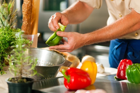 Close up of chef in a commercial restaurant kitchen working; he is preparing vegetablesの写真素材
